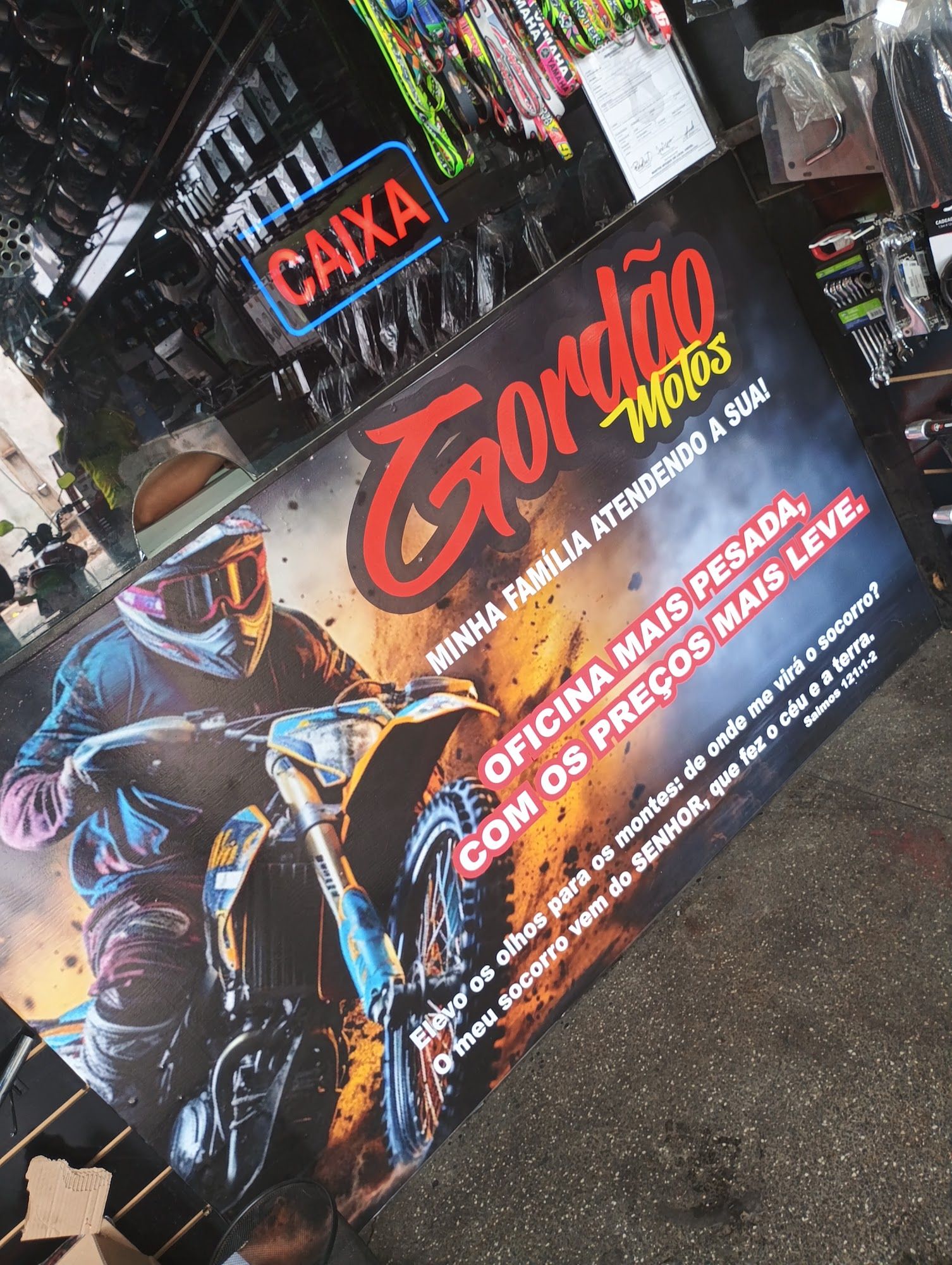 Banner do balcão com o logo Gordão Motos e o slogan da oficina, ao lado do letreiro neon Caixa