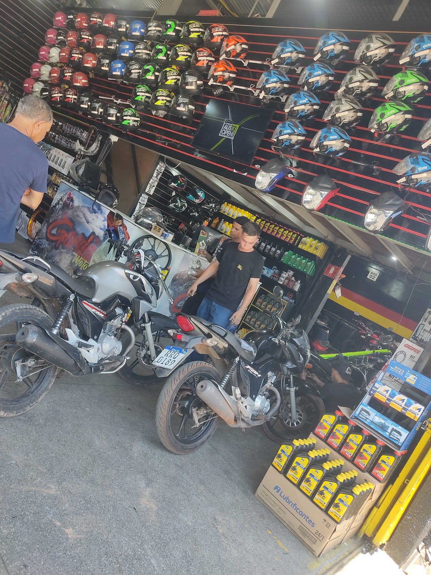 Duas motos paradas em frente ao balcão da Gordão Motos, com funcionário atendendo um cliente