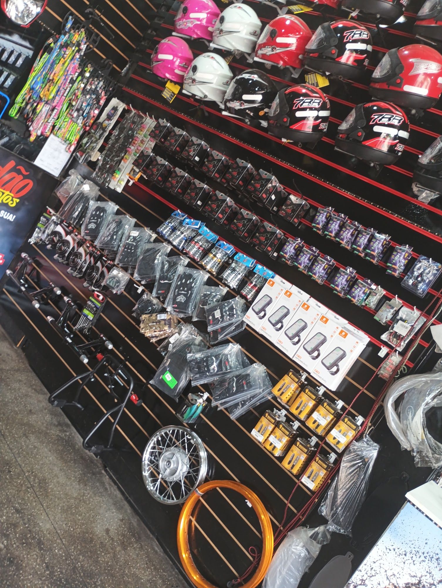 Expositor com capacetes, luvas, capas, manetes, cavaletes e aros de roda